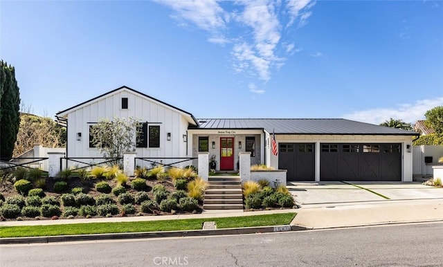 modern farmhouse featuring metal roof, an attached garage, concrete driveway, board and batten siding, and a standing seam roof