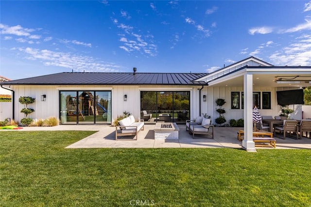 back of property with board and batten siding, a patio area, and a lawn