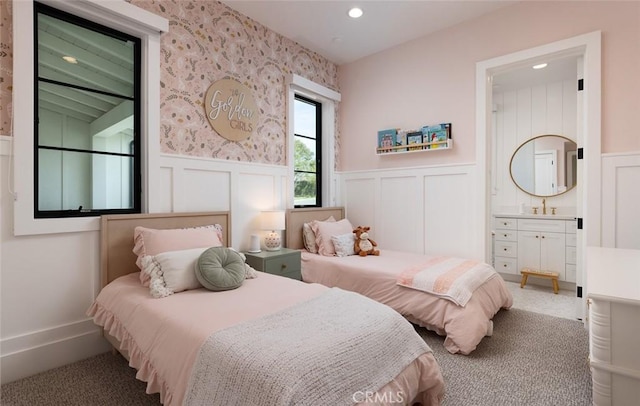 carpeted bedroom featuring recessed lighting, a wainscoted wall, a sink, and ensuite bath