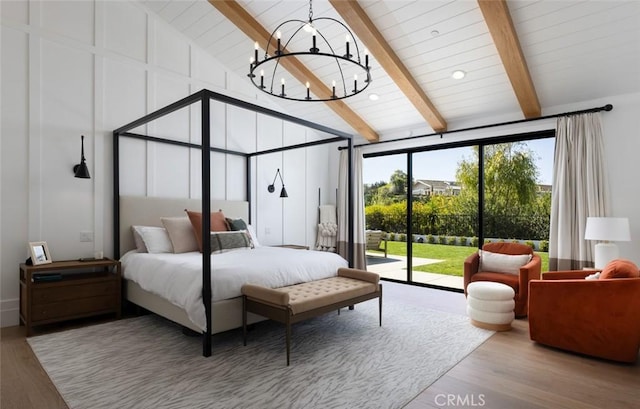 bedroom with vaulted ceiling with beams, an inviting chandelier, wood finished floors, and access to exterior