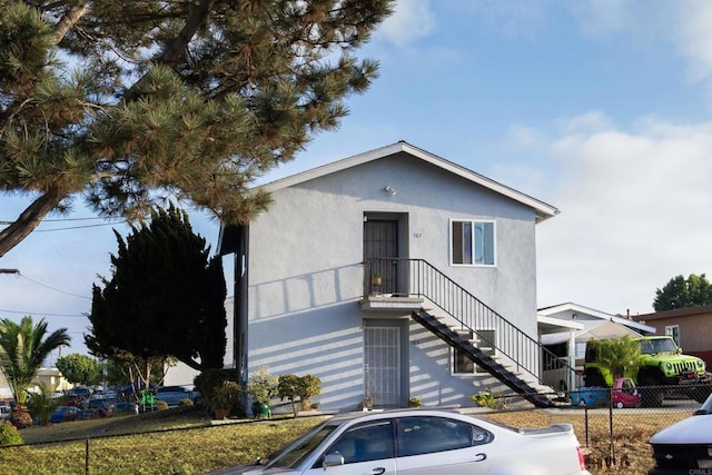 view of front of home featuring stairs, fence, and stucco siding