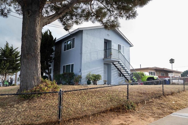 view of front of house with stucco siding, fence, and stairs