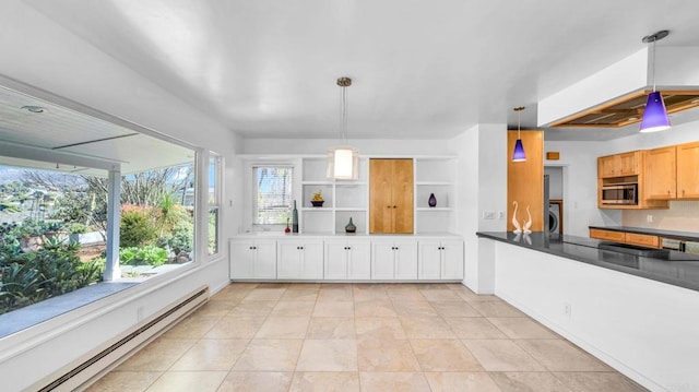 kitchen featuring a baseboard heating unit, white cabinetry, stainless steel microwave, dark countertops, and decorative light fixtures