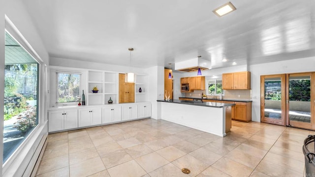 kitchen featuring dark countertops, stainless steel microwave, hanging light fixtures, a baseboard heating unit, and a peninsula