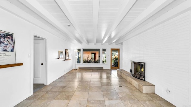 unfurnished living room with a baseboard radiator, beam ceiling, baseboards, and a tiled fireplace