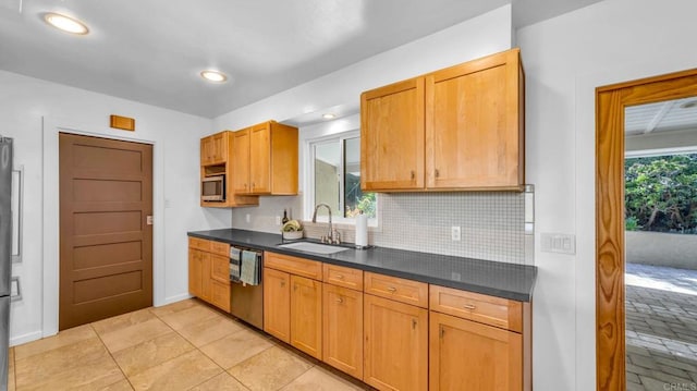 kitchen with tasteful backsplash, dark countertops, appliances with stainless steel finishes, a sink, and plenty of natural light