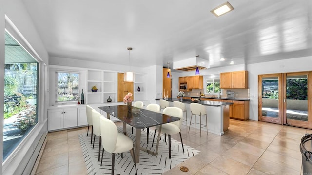 dining area with built in features, baseboard heating, and light tile patterned flooring