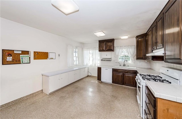 kitchen featuring dark brown cabinetry, under cabinet range hood, white appliances, a sink, and decorative backsplash