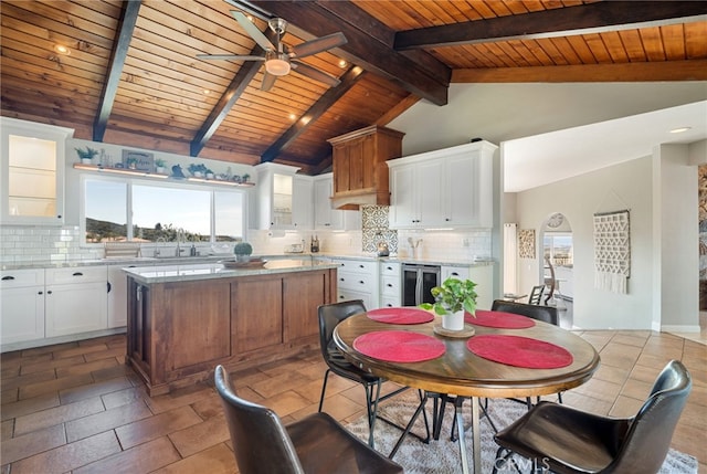 kitchen featuring beverage cooler, a kitchen island, glass insert cabinets, white cabinetry, and backsplash