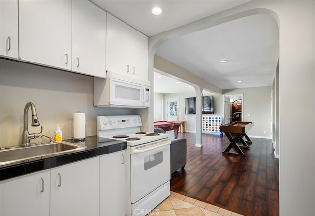 kitchen featuring a sink, dark countertops, white cabinetry, recessed lighting, and white appliances