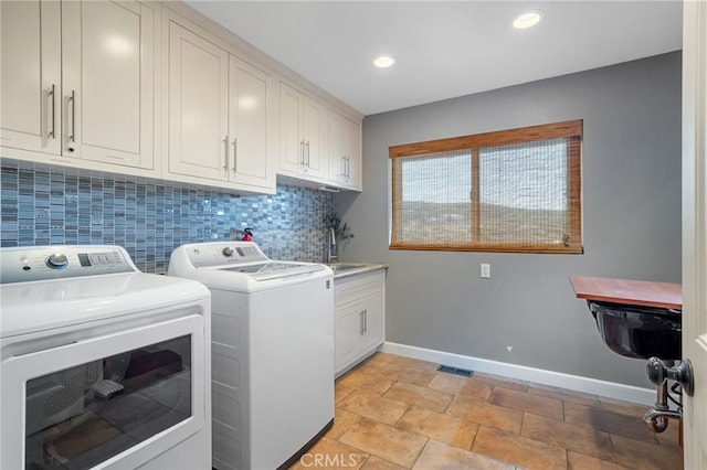 laundry room with visible vents, baseboards, cabinet space, a sink, and washer and dryer