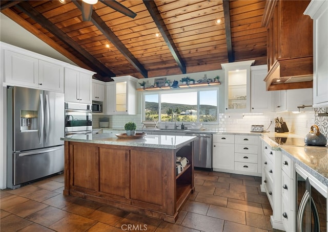 kitchen with light stone countertops, lofted ceiling with beams, stainless steel appliances, decorative backsplash, and glass insert cabinets