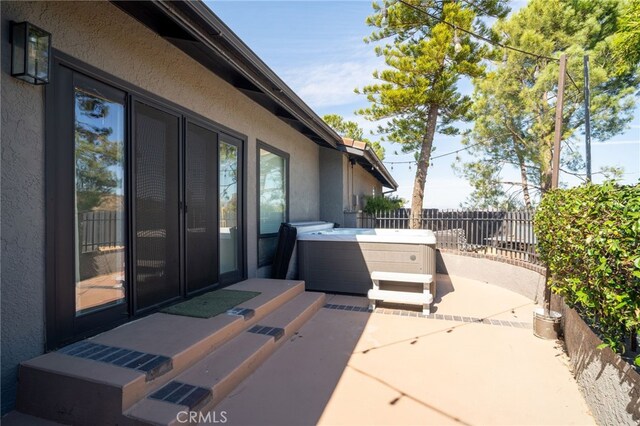 view of patio / terrace with fence, entry steps, and a hot tub