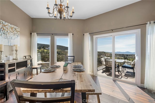 dining space with a mountain view, baseboards, a healthy amount of sunlight, and a chandelier