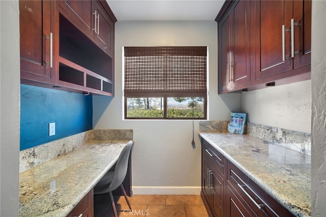 interior space with baseboards, dark brown cabinets, and light stone countertops