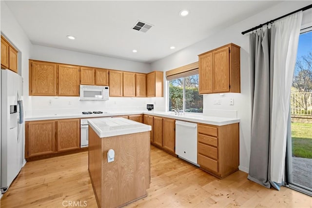 kitchen featuring white appliances, light wood finished floors, visible vents, a center island, and recessed lighting