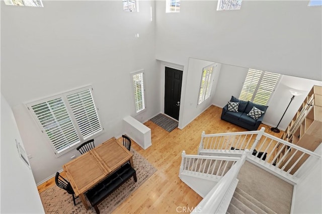 foyer entrance with a towering ceiling, stairs, and wood finished floors