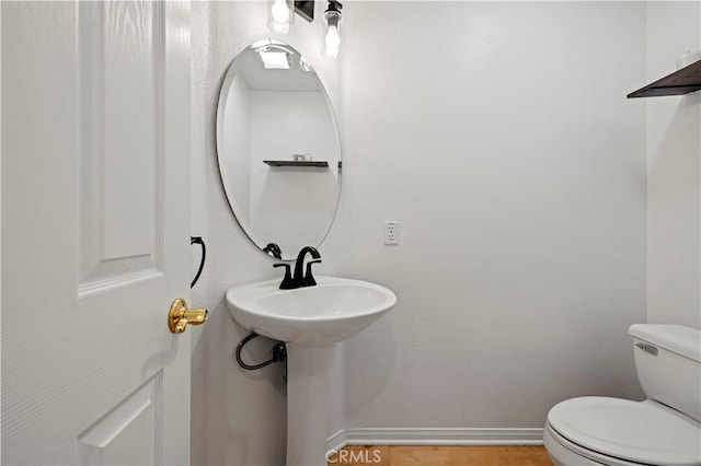 bathroom with baseboards, a sink, and toilet