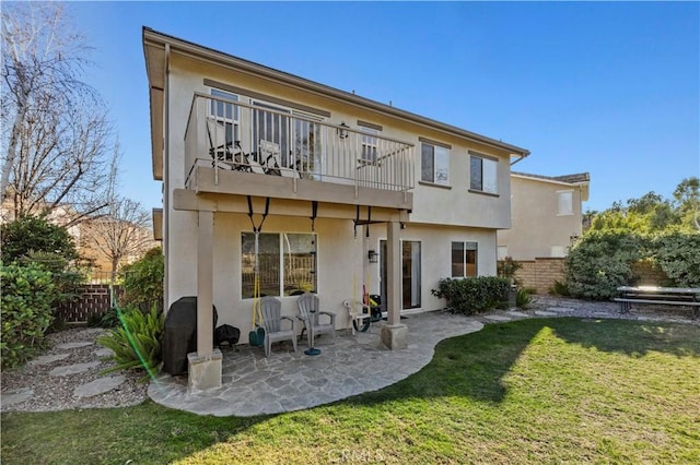 rear view of house featuring stucco siding, fence, a patio, and a yard