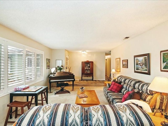 living room with light carpet, visible vents, and a textured ceiling