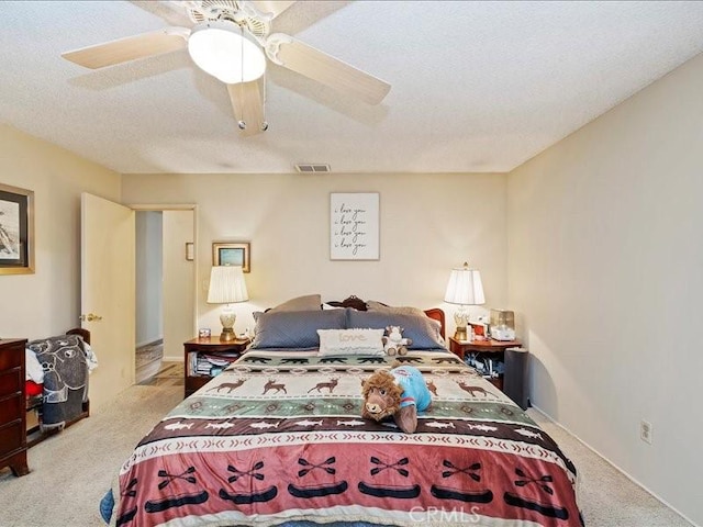 carpeted bedroom with visible vents, a textured ceiling, and ceiling fan