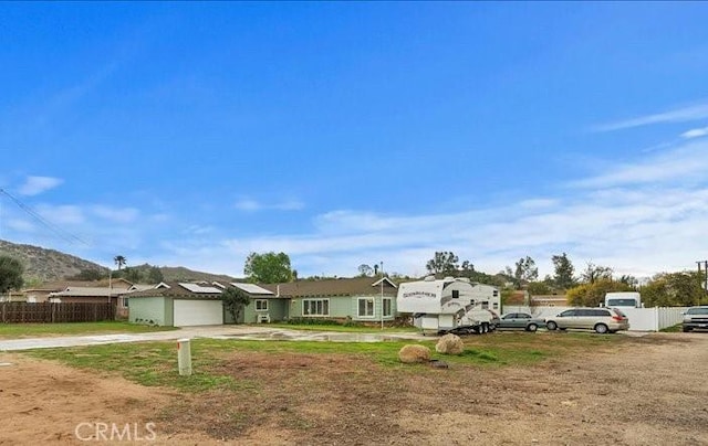 single story home featuring solar panels, concrete driveway, a garage, and fence