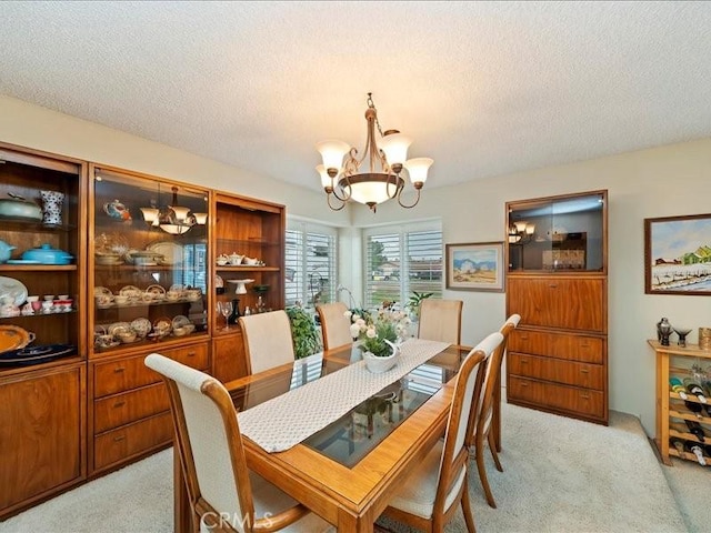 dining space with a textured ceiling, a notable chandelier, and light carpet