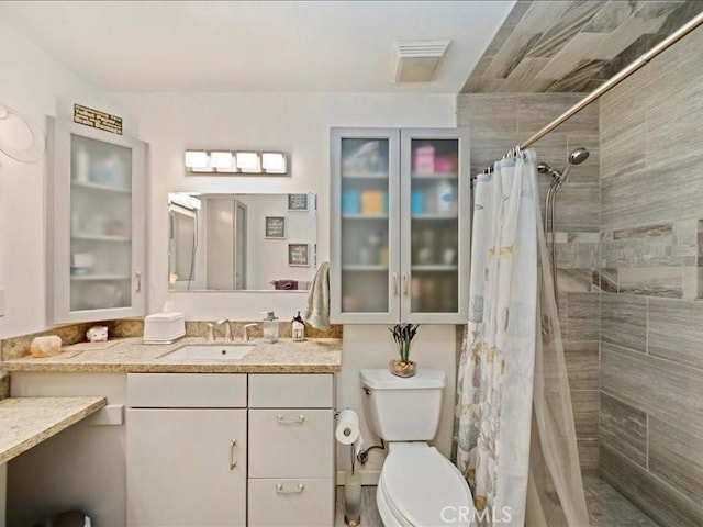 full bath featuring tiled shower, toilet, and vanity