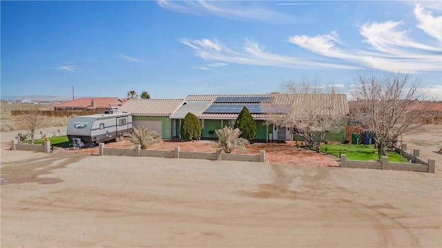 view of front of house with roof mounted solar panels, a tile roof, and an attached garage