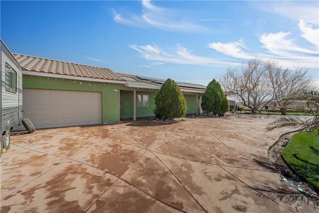 view of front of house with a garage, driveway, a tile roof, and stucco siding