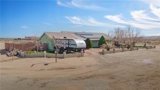 view of front of home featuring roof mounted solar panels and fence