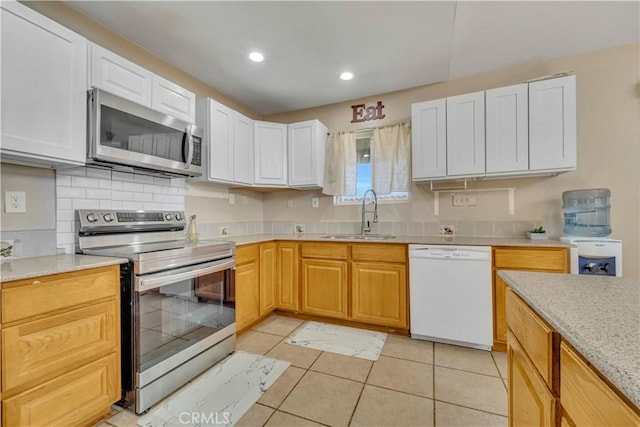 kitchen featuring appliances with stainless steel finishes, white cabinets, and a sink