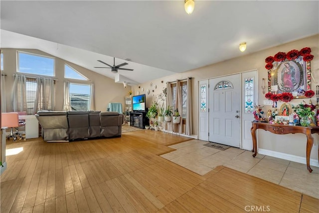 foyer featuring a ceiling fan, vaulted ceiling, and light wood finished floors