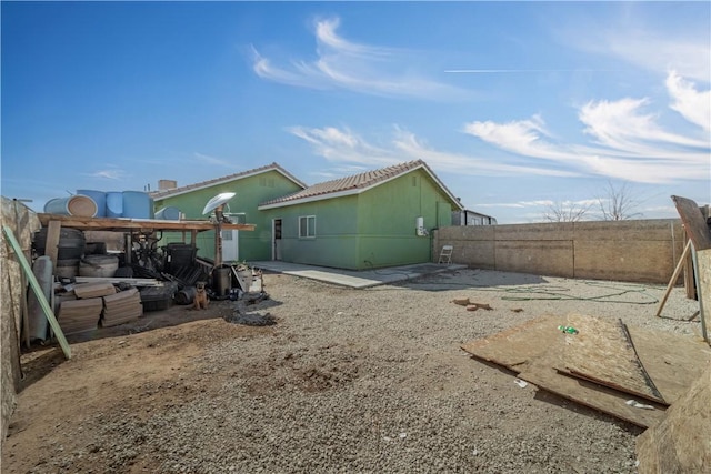 back of house with a tile roof, a fenced backyard, and a patio