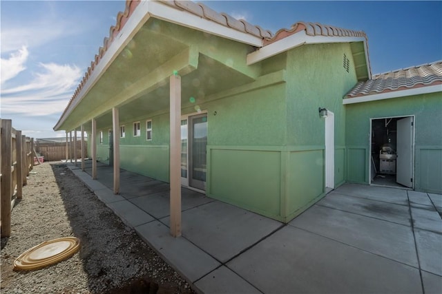 view of property exterior with a patio, a fenced backyard, a tiled roof, and stucco siding