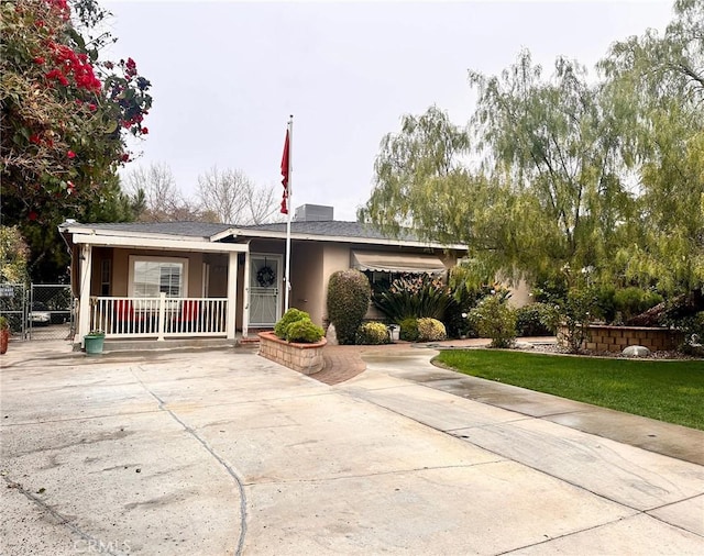 ranch-style home featuring a porch, a front lawn, and stucco siding