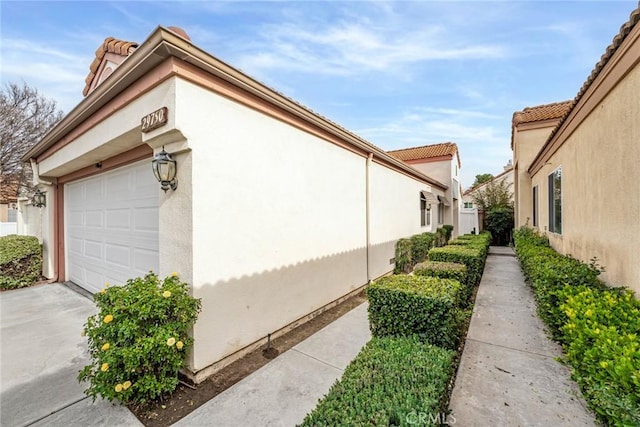 view of home's exterior with an attached garage, concrete driveway, and stucco siding