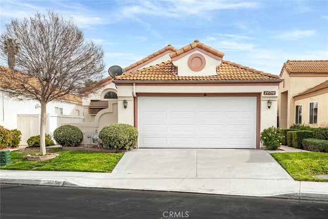 mediterranean / spanish-style house with driveway, a tiled roof, a garage, and stucco siding