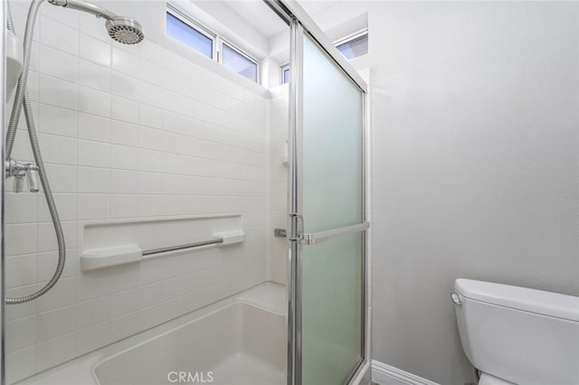 bathroom featuring a shower with door and toilet