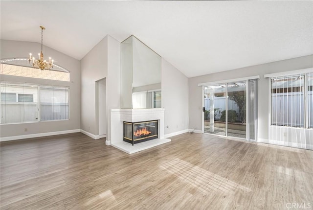 unfurnished living room with a glass covered fireplace, lofted ceiling, and wood finished floors