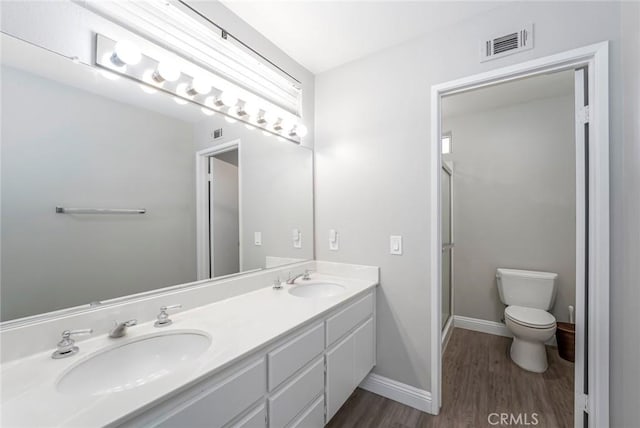 bathroom featuring toilet, visible vents, a sink, and wood finished floors