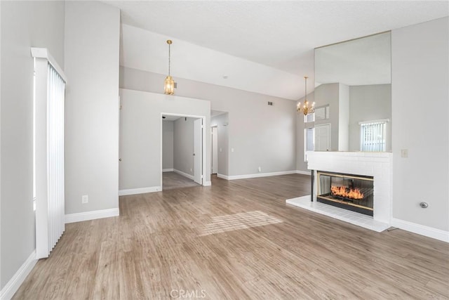 unfurnished living room with lofted ceiling, light wood-style flooring, a fireplace, and baseboards