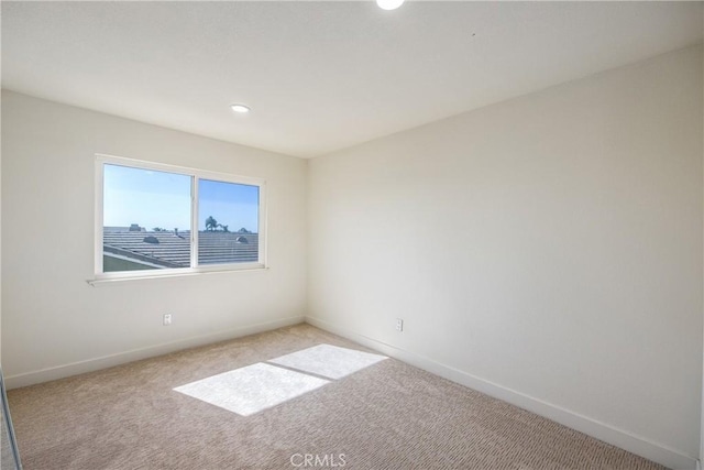 spare room featuring light carpet, recessed lighting, and baseboards