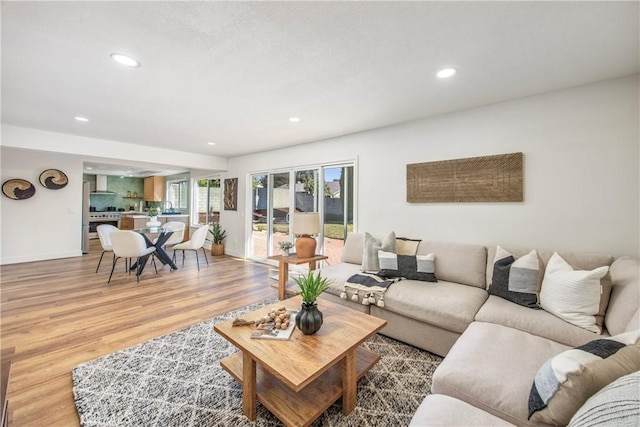 living area featuring baseboards, light wood-type flooring, and recessed lighting