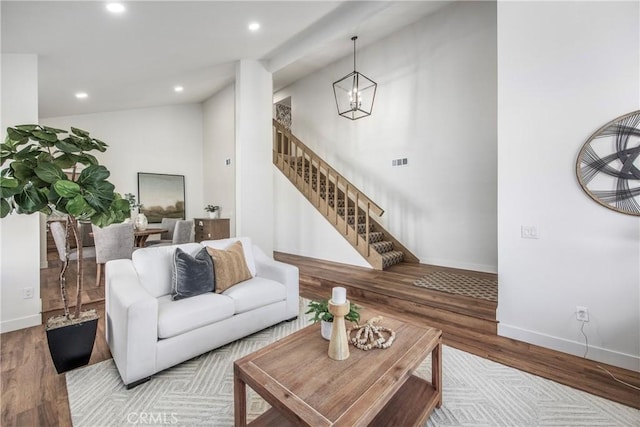 living area with an inviting chandelier, stairs, wood finished floors, and recessed lighting