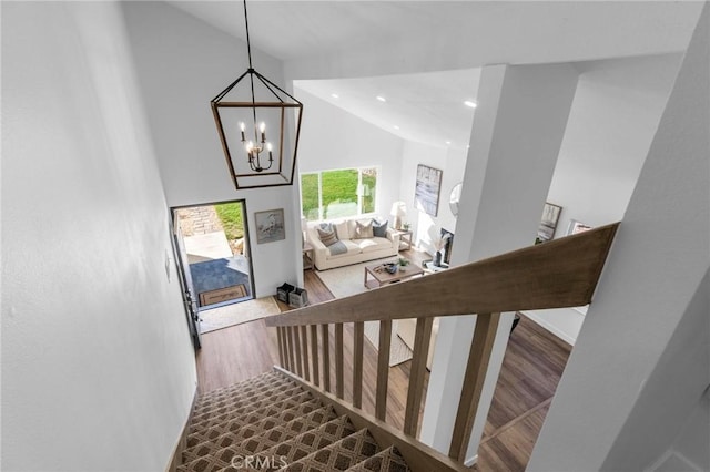 stairs featuring high vaulted ceiling, recessed lighting, an inviting chandelier, and wood finished floors