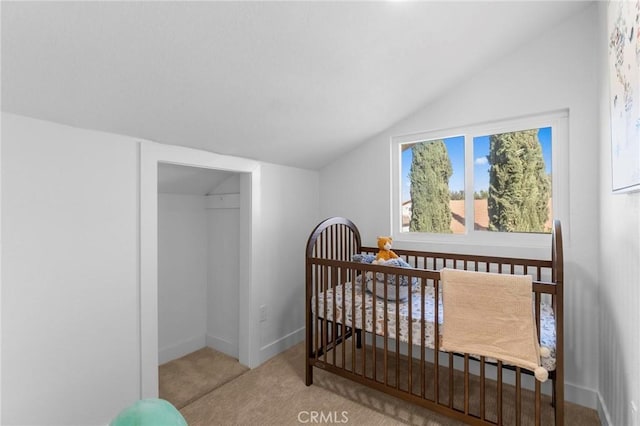 carpeted bedroom featuring vaulted ceiling, a crib, and baseboards