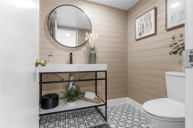 half bathroom featuring wood walls and toilet