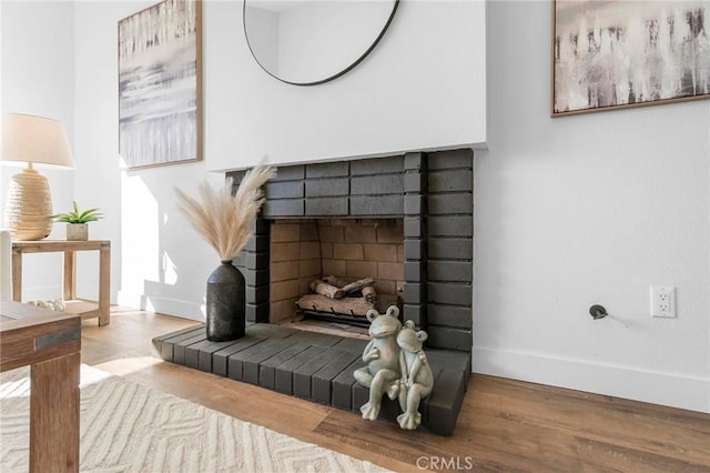 interior details featuring a brick fireplace, wood finished floors, and baseboards