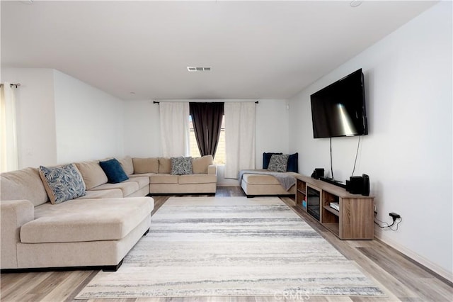 living area with light wood-style floors and visible vents